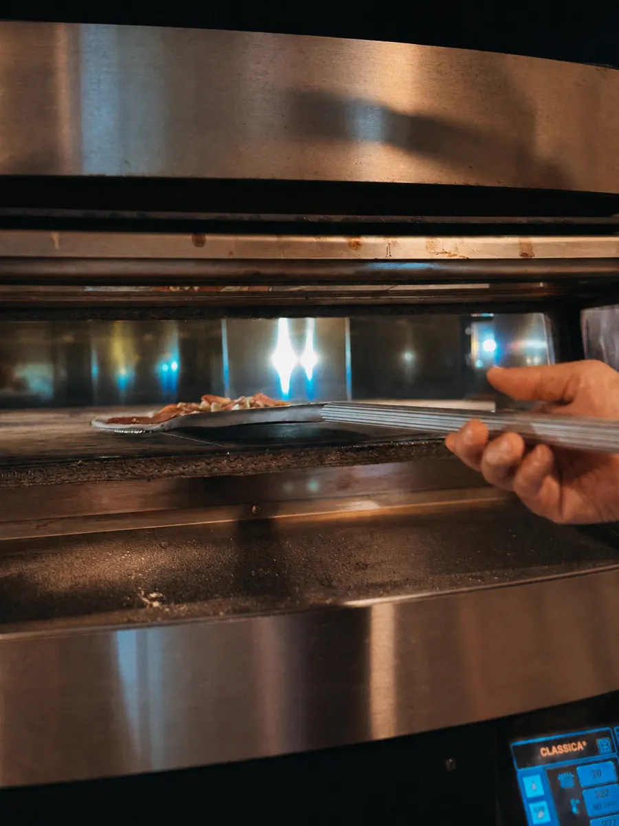 Pizza wird in den Ofen geschoben